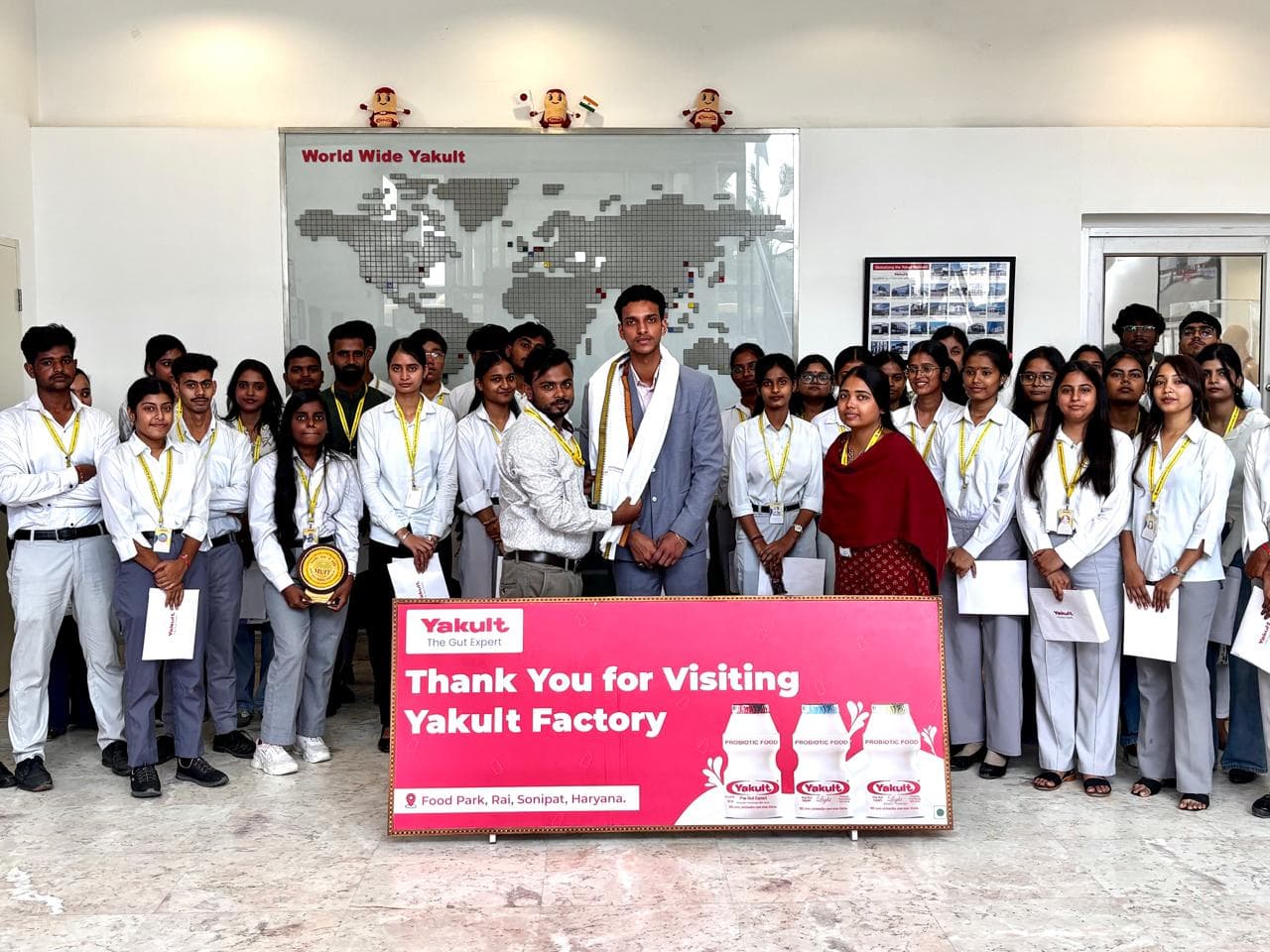 Faculty felicitating the Yakult host with a shawl, surrounded by students